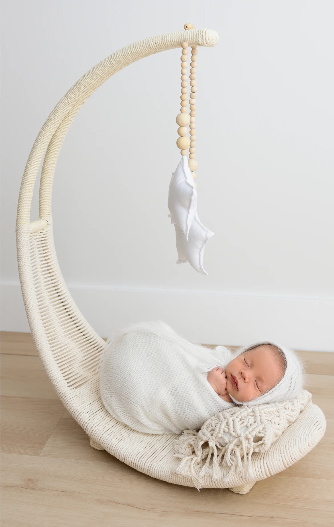 Newborn sleeping in a woven moon cradle